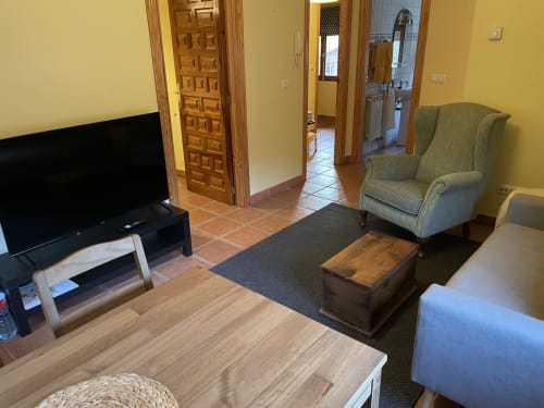 Sala de estar del apartamento Monte Roblo con televisor, sillón, muebles de madera y vistas a la montaña en Salamon