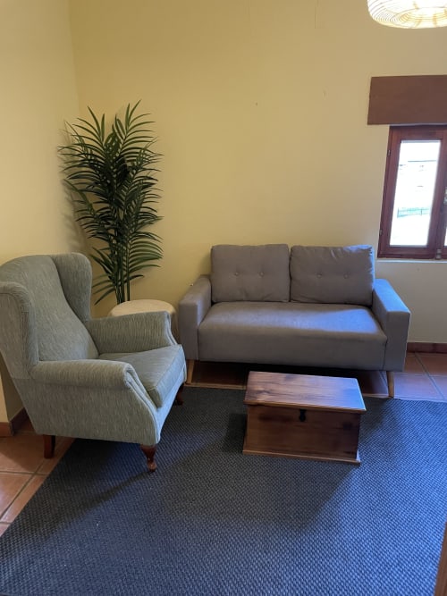 Acogedora sala de estar en apartamento Monte Roblo con sofá gris, butaca rayada, mesa de madera y vistas a la montaña en Salamón