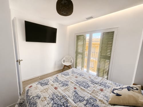 Nowoczesna sypialnia z telewizorem, drzwiami balkonowymi z widokiem na morze, parkietem i pościelą w wzory w Cantos de Sirena, Torremolinos