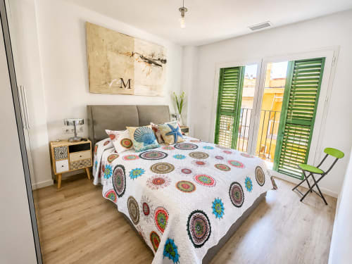 Jasna sypialnia w apartamencie Torremolinos z kolorową pościelą w wzory, szarym zagłówkiem i zielonym balkonem