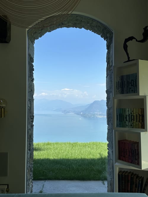 Stone archway framing Lake Maggiore view with green grass, mountains, and blue sky from luxury spa retreat in Stresa, Italy