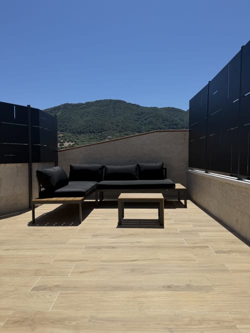 Ampia terrazza panoramica a Borgo Albador con sedute lounge nere, ponte in legno e vista sulle montagne di Torpè