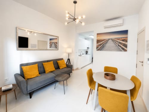 Nowoczesny salon apartamentowy z szarą sofą, żółtymi krzesłami, stołem jadalnym i kuchnią w Torremolinos