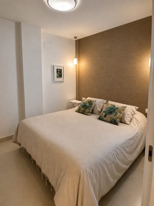 Nowoczesna sypialnia w apartamencie w Torremolinos z łóżkiem queen-size, złotą ścianą akcentową i współczesnym oświetleniem