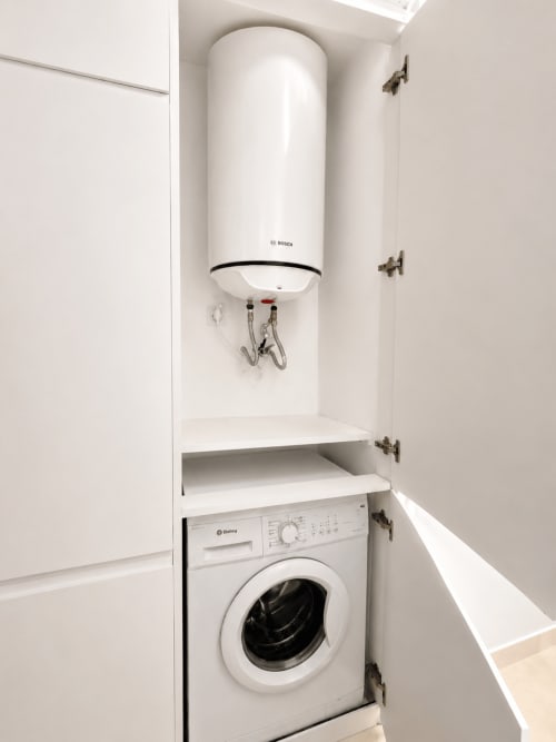 Mała pralnia w apartamencie w Torremolinos z białą pralką i podgrzewaczem wody Bosch w szafce