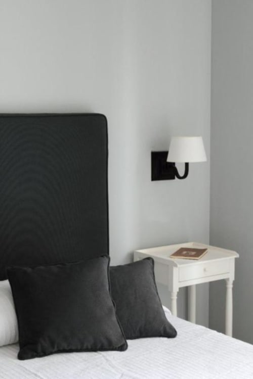 Camera moderna del B&B Le Biciclette con testata nera, comodino bianco, applique murale e cuscini decorativi neri