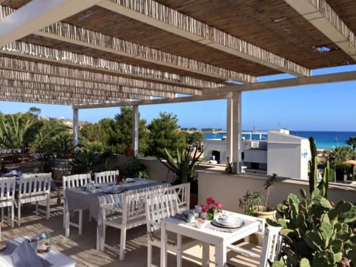 Terrazza fronte mare con arredamento bianco, vista sul mare e pergolato ombreggiante presso B&B Le Biciclette a San Vito Lo Capo, Sicilia