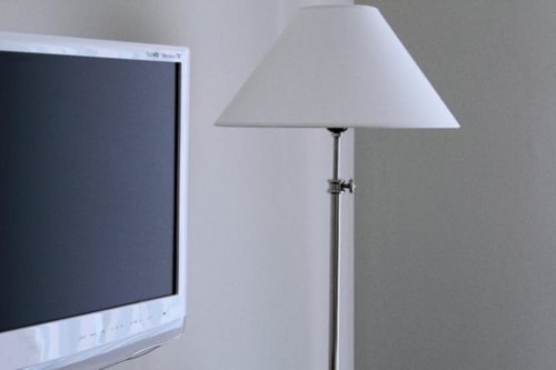 Lampada da terra moderna con paralume bianco accanto a TV a schermo piatto nella Double Room di B&B Le Biciclette, San Vito Lo Capo