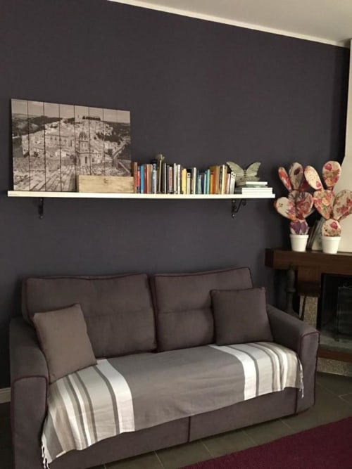 Accogliente angolo lettura a B&B Le Biciclette a San Vito Lo Capo con divano marrone, ripiano sospeso, libri e succulente in vaso