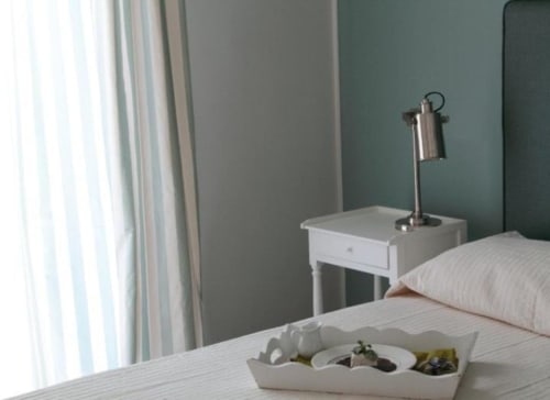 Camera luminosa al B&B Le Biciclette di San Vito Lo Capo con letto bianco, lampada da comodino e vassoio di benvenuto