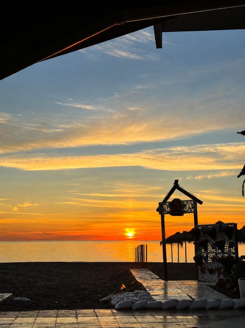 Widok na zachód słońca z tarasu nad morzem w Alquileres Cantos de Sirena, Torremolinos, złote niebo odbijające się w morzu