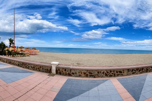 Promenada nadmorska w Alquileres Cantos de Sirena w Torremolinos z piaszczystą plażą, błękitnym morzem i palmami