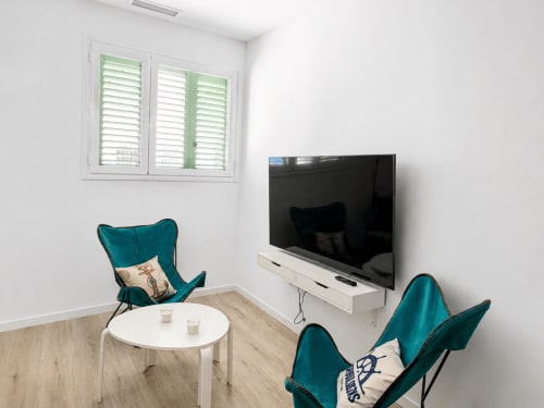 Nowoczesny salon w Alquileres Cantos de Sirena, Torremolinos z turkusowymi fotelami, telewizorem plaskim i drewnianą podłogą