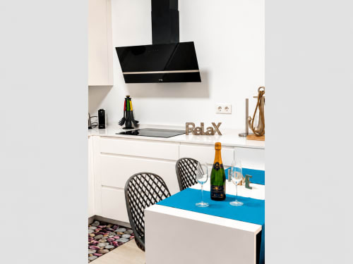 Nowoczesna kuchnia-jadalnia w apartamencie Torremolinos z niebieskim stołem, czarnym okapem i urządzeniami ze stali nierdzewnej