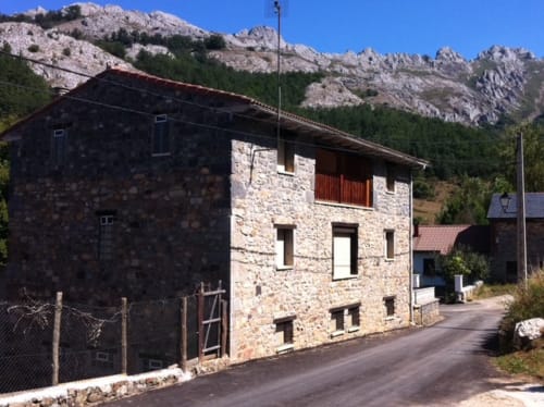 Edificio de piedra Monte Roblo en Salamón con vistas a la montaña, arquitectura rústica y tejado de tejas rojas