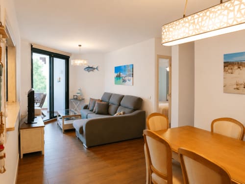 Nowoczesny salon w Torremolinos z szarą sofą, drewnianym stołem jadalnym, dekoracją o morskiej tematyce i dostępem do tarasu