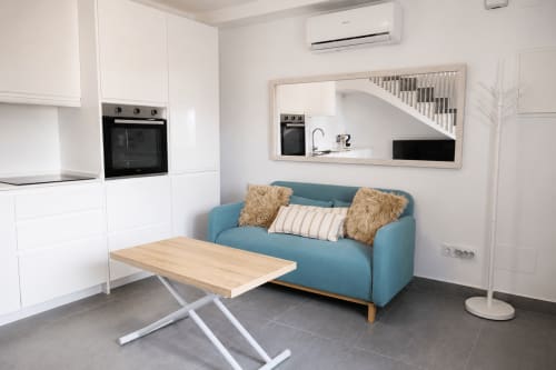Nowoczesny otwarty apartament w Torremolinos z niebieską sofą, białą kuchnią, drewnianym stołem i widokiem na schody