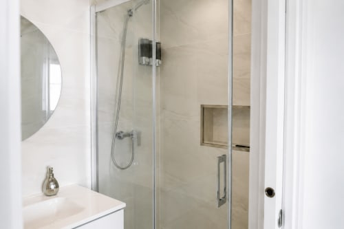 Nowoczesna łazienka z marmurową kabiną prysznicową, szklannymi drzwiami i białą umywalką w apartamencie Alquileres Cantos de Sirena