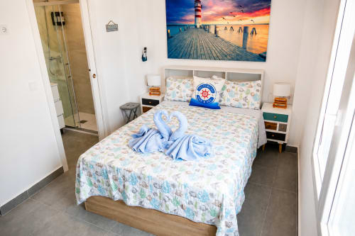 Sypialnia apartamentu z widokiem na plażę w Torremolinos z sztuką morską, niebieskimi łabędziami z ręczników i łazienką przylegającą