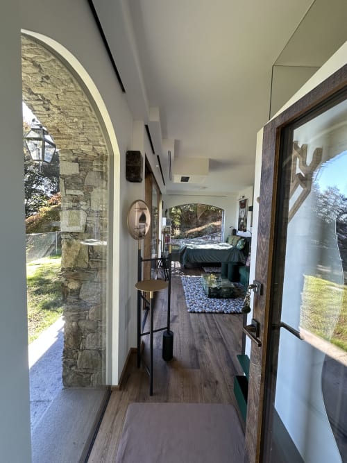 Modern luxury studio with wood flooring, archway door to stone terrace, lake views, and minimalist furnishings at Stresa