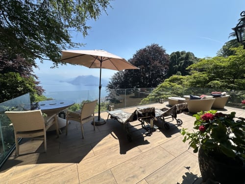 Luxury terrace overlooking Lake Maggiore in Stresa with lounge chairs, umbrella, and garden views at private spa retreat