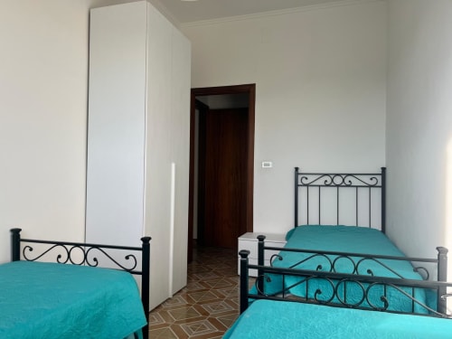 Due letti singoli gemelli con biancheria turchese e testiere in ferro nell'appartamento Il Corso Guest House a Veglie, Italia
