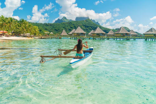 Femme dans un bateau récoltant des algues près des bungalows sur l'eau Fare Tihi Moana, Uturoa, Polynésie française