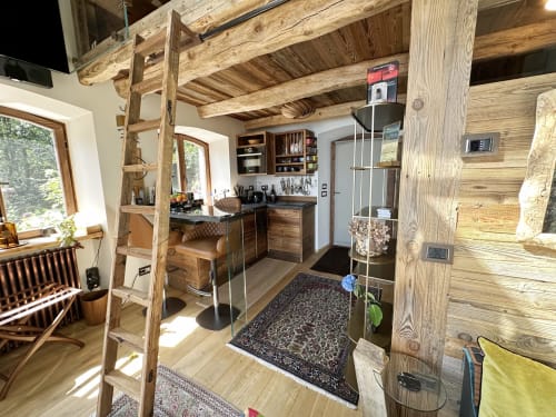 Interno di lussuoso chalet con travi in legno, angolo cottura, scala per soppalco e arredamento moderno con vista sul Lago Maggiore