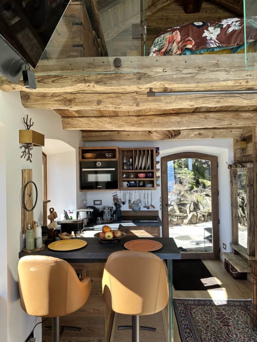Cucina di lusso con travi in legno, piano cottura nero, sedie gialle e vista lago presso la spa Stresa
