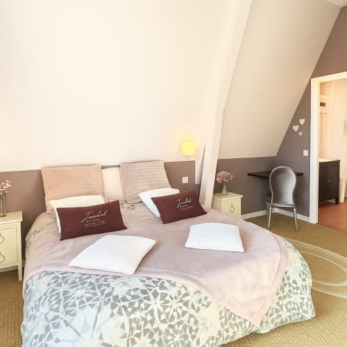 Chambre pastel à l'hôtel Maunoury Citybreak à Chartres avec lit rond, oreillers bordeaux et équipements modernes