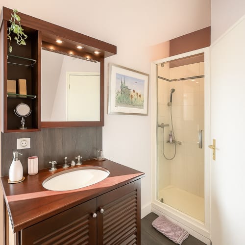 Salle de bain moderne de l'hôtel Maunoury Citybreak à Chartres avec meuble en bois, lavabo ovale, miroir encadré et douche à l'italienne