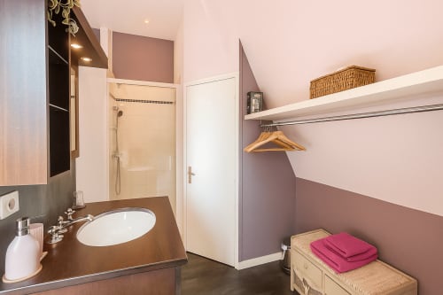 Salle de bains moderne de la chambre Pastel à l'hôtel Maunoury Citybreak de Chartres avec meuble vasque marron, douche et serviettes roses