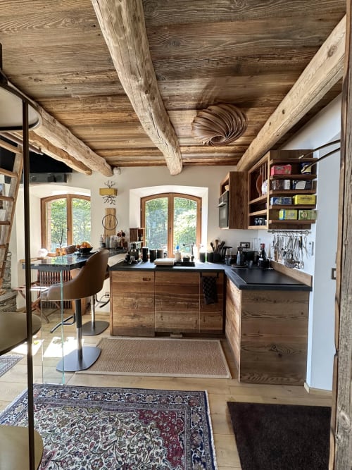 Cucina di lusso con travi in legno a vista, top neri e mobili in legno con vista sul Lago Maggiore