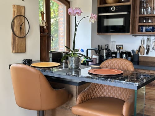 Raffinata zona pranzo con sedie in pelle marrone chiaro, tavolo in marmo, composizione di orchidee e vista lago a Stresa