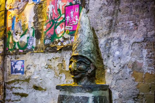 Street art and bronze bust sculpture on weathered wall at Suite Maradona, Naples boutique hotel