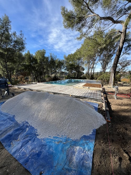 Construction de la piscine Mas Misajail au Castellet avec base en gravier et arbres environnants sous ciel bleu