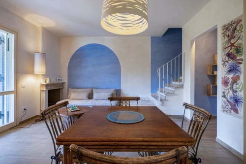 Modern villa in Sardinia with dining area, blue accent wall, wooden table, and contemporary furnishings