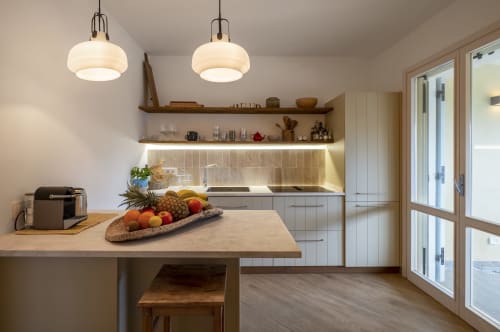 Modern kitchen with pendant lights, wooden shelves, and island seating at Top Villas Sardinia in Quartu Sant'Elena