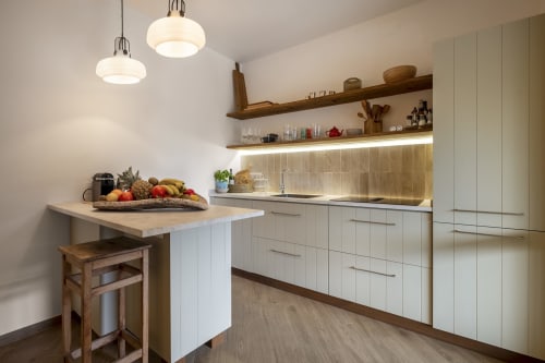 Modern kitchen at Top Villas Sardinia with white cabinetry, wooden shelving, pendant lights, and island seating in Quartu