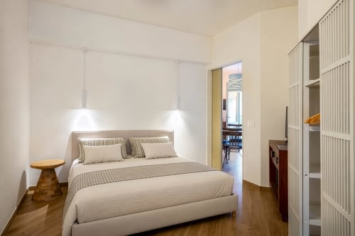 Modern bedroom at Top Villas Sardinia with queen bed, pendant lighting, wooden floors, and ensuite access in Quartu