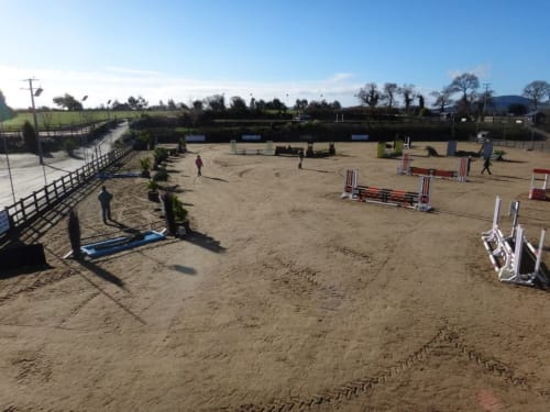 Equestrian jumping arena at Boswell Equestrian Centre in Ashford with jumps, fencing, and countryside views