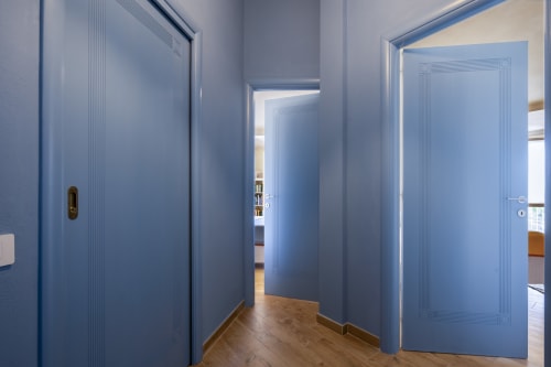 Modern hallway with blue doors at Top Villas Sardinia, Quartu Sant'Elena, featuring wooden flooring and minimalist design