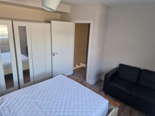 Spacious bedroom at Boswell Equestrian Centre with double bed, white wardrobe, black sofa, and wooden flooring in The Old