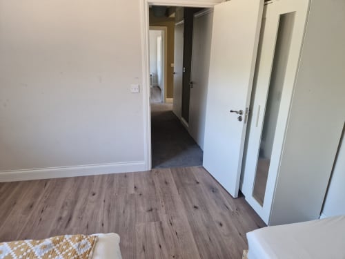 Spacious bedroom in The old Store apartment at Boswell Equestrian Centre with wood flooring, white doors, and neutral décor