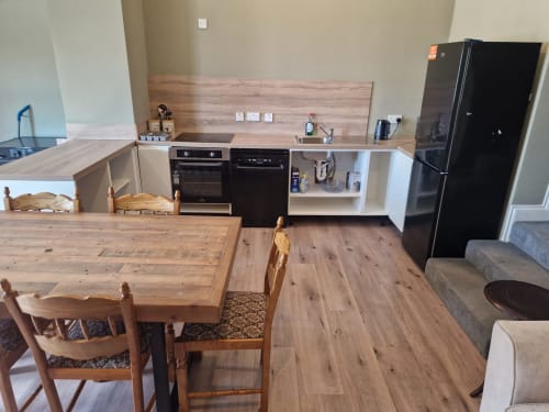 Modern kitchen and dining area at Boswell Equestrian Centre's 'The Old Store' apartment in Ashford with wooden table,