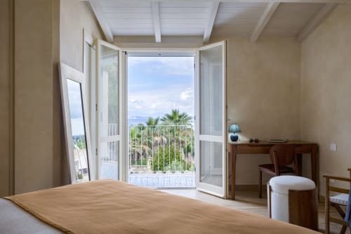 Luxury bedroom at Top Villas Sardinia with panoramic sea views, palm trees, and direct terrace access