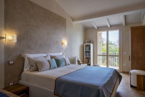 Modern bedroom at Top Villas Sardinia with blue bedding, textured accent wall, and balcony views in Quartu Sant'Elena