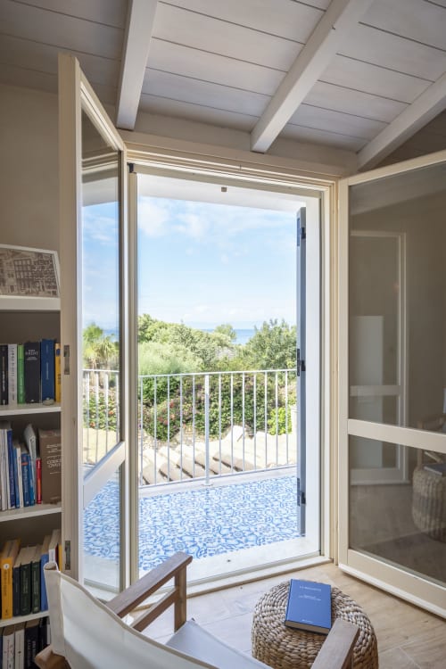 Modern villa bedroom with open glass doors overlooking Mediterranean sea and garden, Quartu Sant'Elena, Sardinia