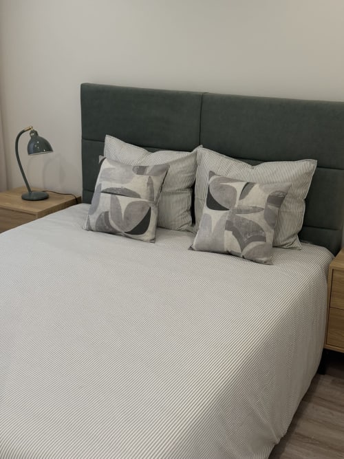 Quarto moderno em Vila Sotto Mayor com cabeceira escura, roupa de cama listrada e almofadas geométricas em Figueira da Foz
