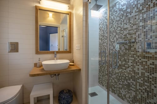 Modern bathroom at Top Villas Sardinia with oval sink, mosaic shower, and wooden vanity